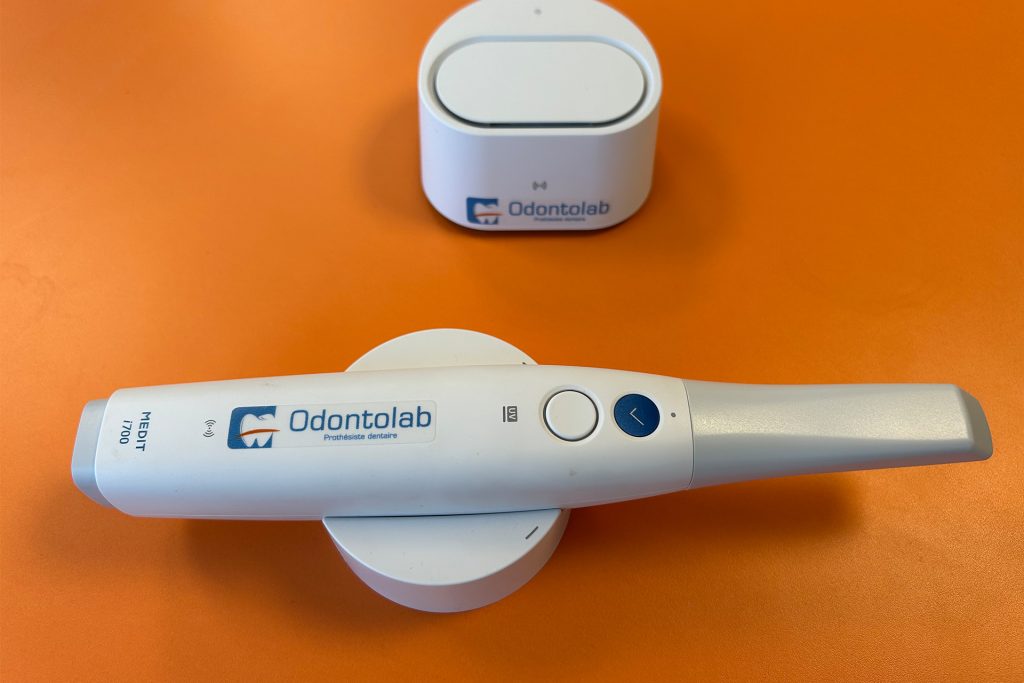 Scanner d'empreinte numérique Medit i700 avec le logo du laboratoire de prothèses dentaires Odontolab posé dessus