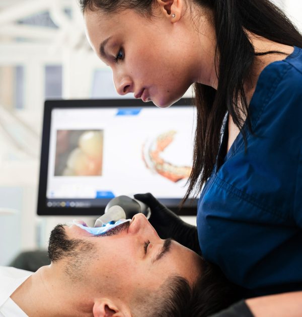 Dentiste utilisant un scanner intra-oral pour prise d'empreinte numérique sur une patiente.